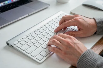 Mains sur un clavier Apple Magic Keyboard montrant la touche antislash en gros plan